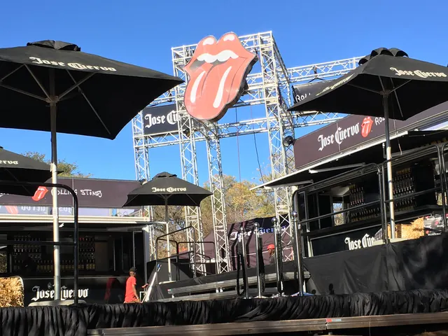Jose Cuervo event bars under black umbrellas, with a giant Rolling Stones tongue on a truss tower