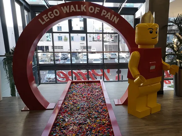 A LEGO activation: a giant minifigure beside a red arch over a path of LEGO bricks