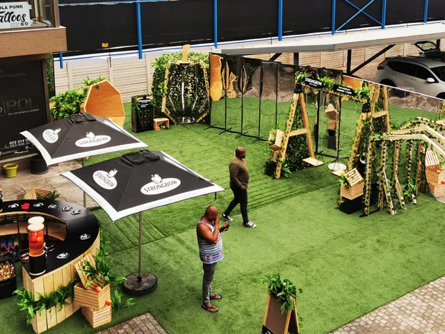 A Strongbow garden activation with artificial lawn, branded umbrellas, a timber bar and giant planted letters
