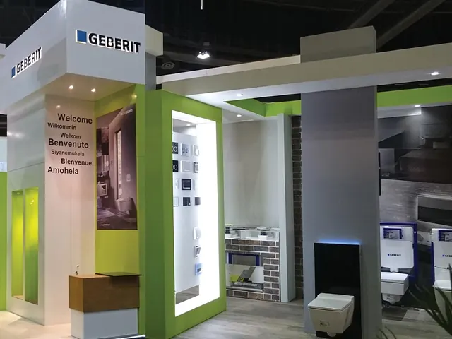 A Geberit stand with green-framed bathroom displays and a multilingual welcome wall