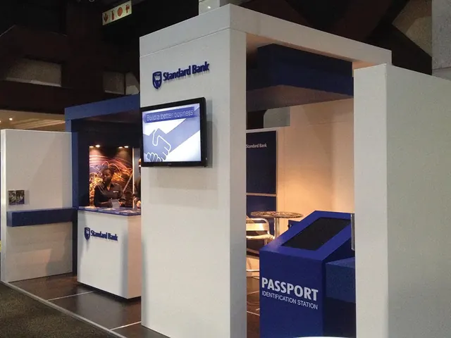 A white Standard Bank exhibition stand with a screen tower and a passport verification station