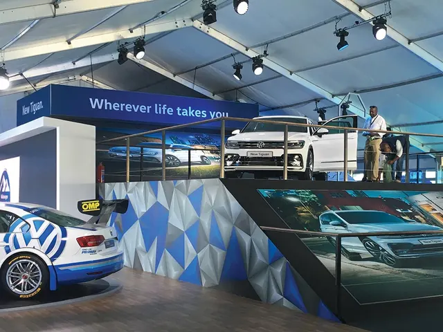 A raised Volkswagen stand under a marquee roof, with the new Tiguan on a platform above a race car