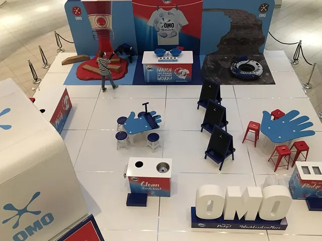 An OMO mall activation seen from above: a white platform with blue furniture and giant OMO letters