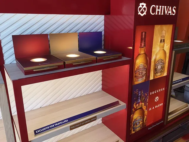 A Chivas Regal travel-retail display in red and gold with lit shelves for bottles
